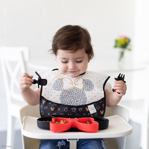 baby in disney black and white bib looking at minnie mouse dish