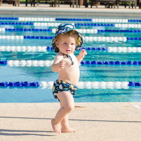 toddler in swim outfit walking near pool