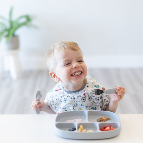 happy baby eating from a divided toddler plate