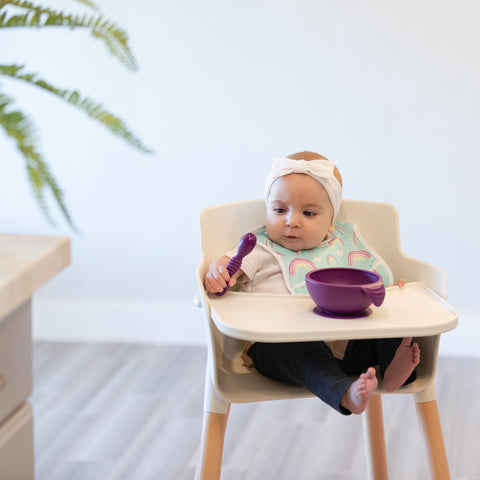 toddler looking at silicone baby spoon in high chair