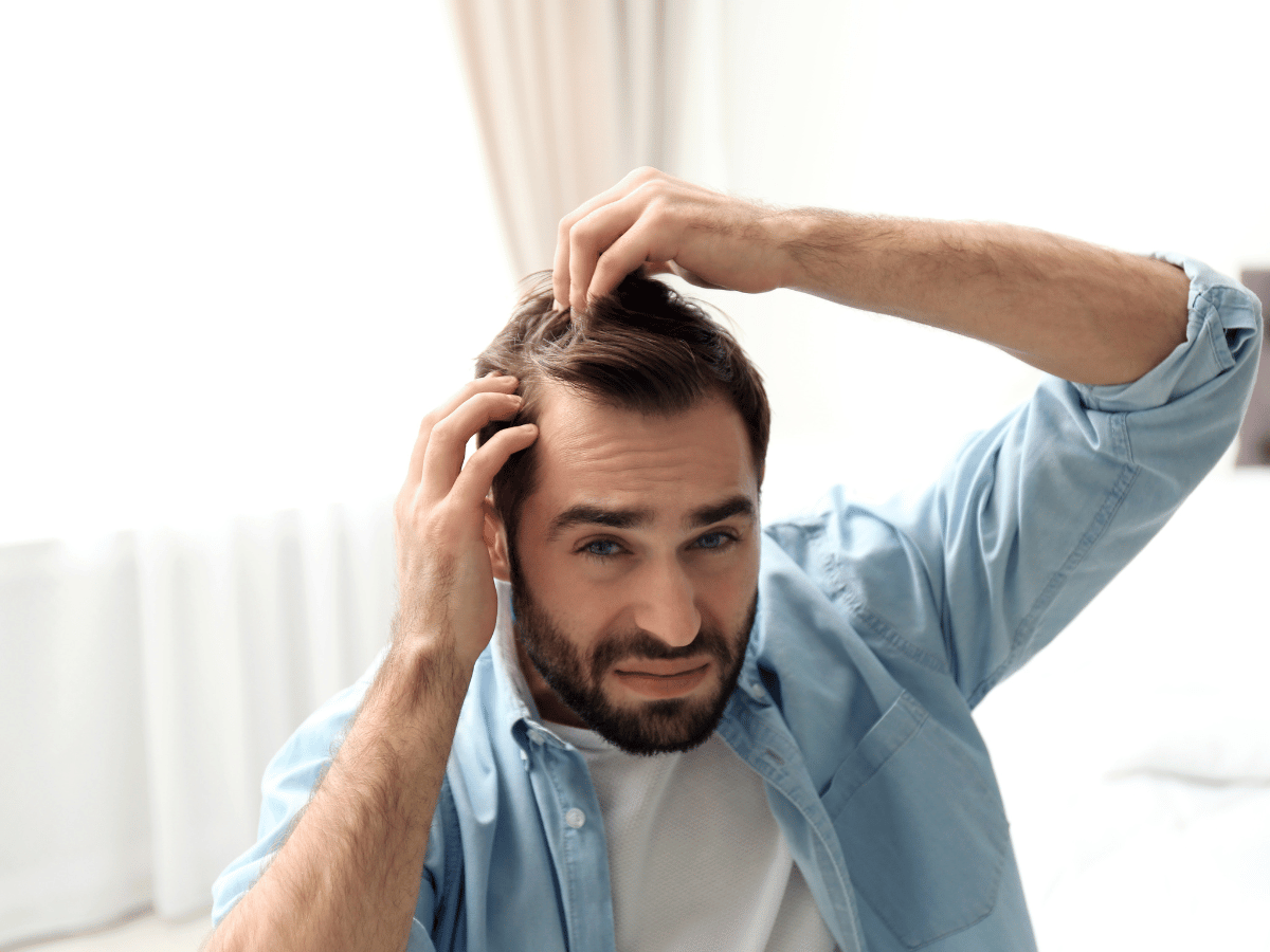 Propriétaire de chat qui regarde dans ses cheveux en se demandant s'il a attrapé les puces de son chat.