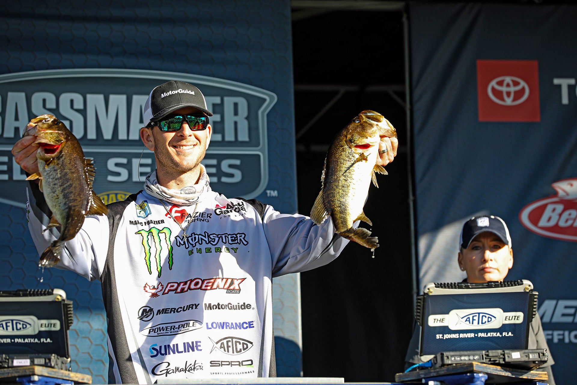 Marc Frazier holding up two bass on the bassmaster elite series stage
