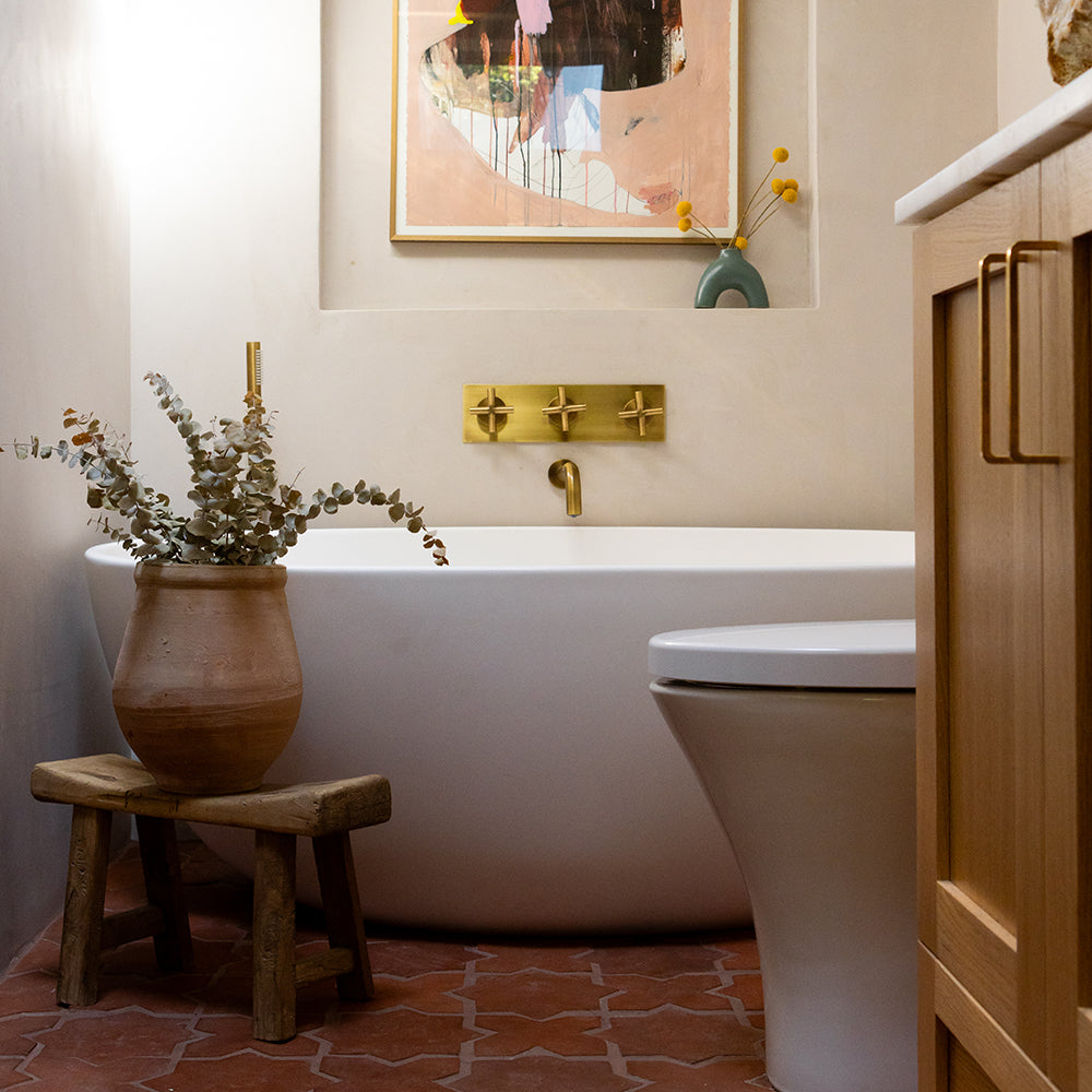 Earth inspired bathroom tub area with terracotta tile floor, white wall, and white tub.