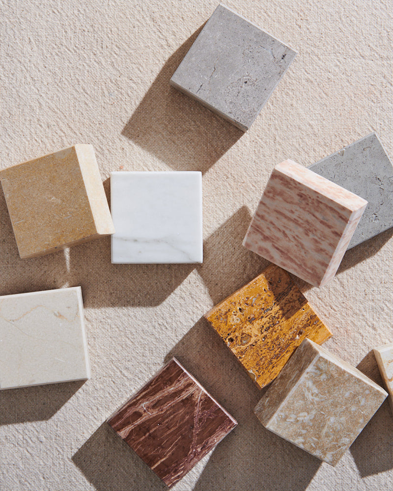 Overhead shot of various square stone tile samples against a natural background.