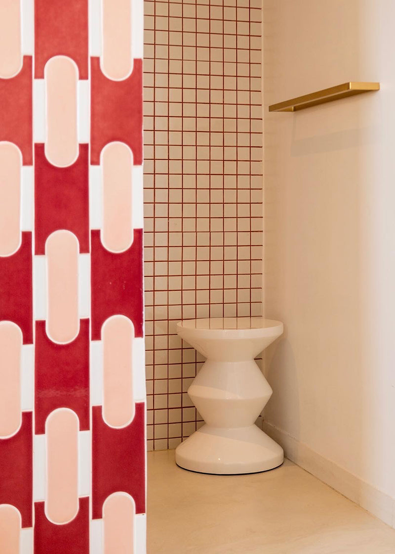 Modern white and red shower area with geometric red tile wall and red grount around white square tile.