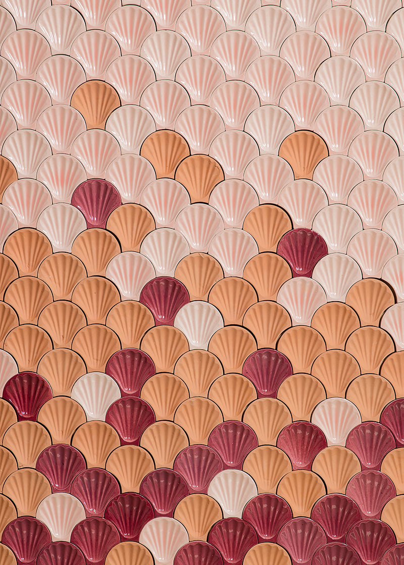 Beautiful wall shell shaped tile arranged in a sunset of hues from red and orange to light pink.