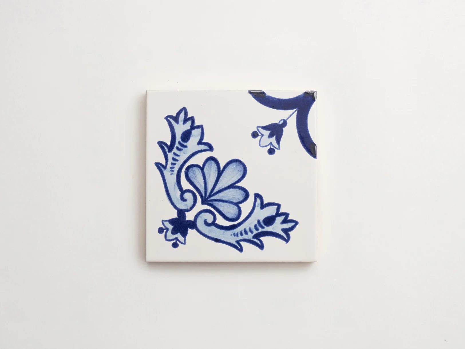 blue and white hand painted tile with floral motifs