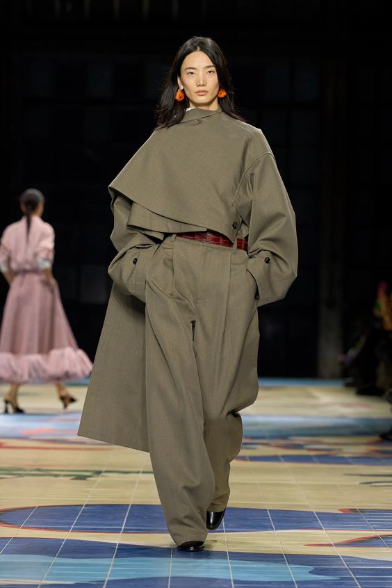 woman walking on runway wearing a green dress and leather belt