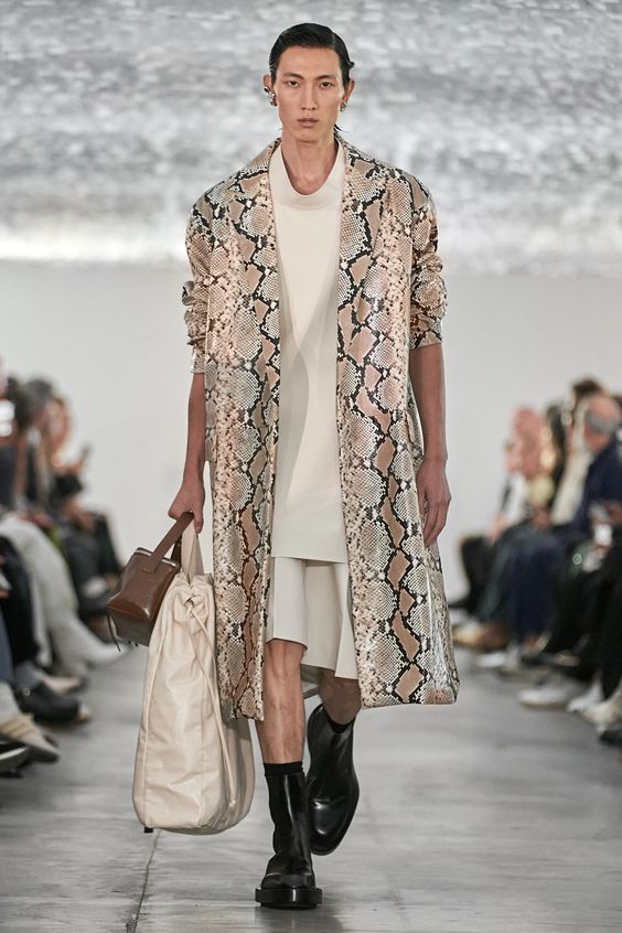 woman walking on runway wearing snakeskin coat and a white dress