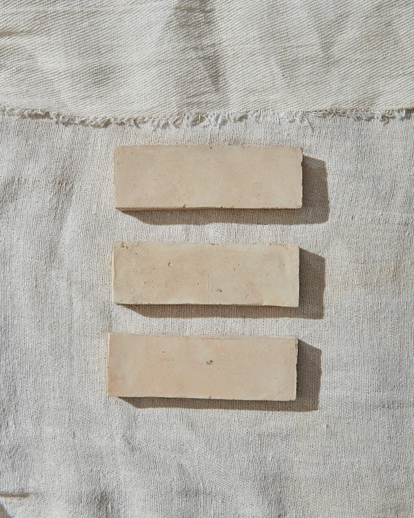 three beige rectangular zellige tiles against a white linen background
