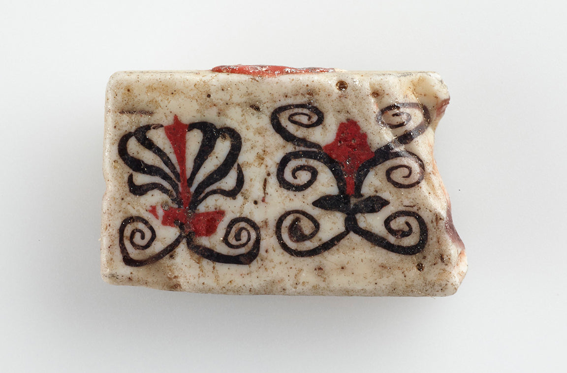 Fragment of a stone mosaic from Egypt, painted with a black and red design.