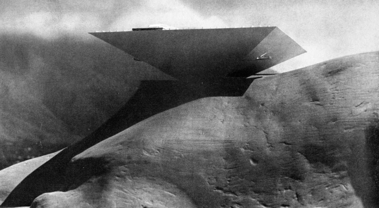 An inverted pyramid building overhangs a cliff.