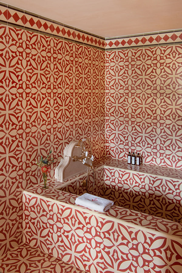 A bathroom with walls and bathtub clad in the same red and cream tiles.
