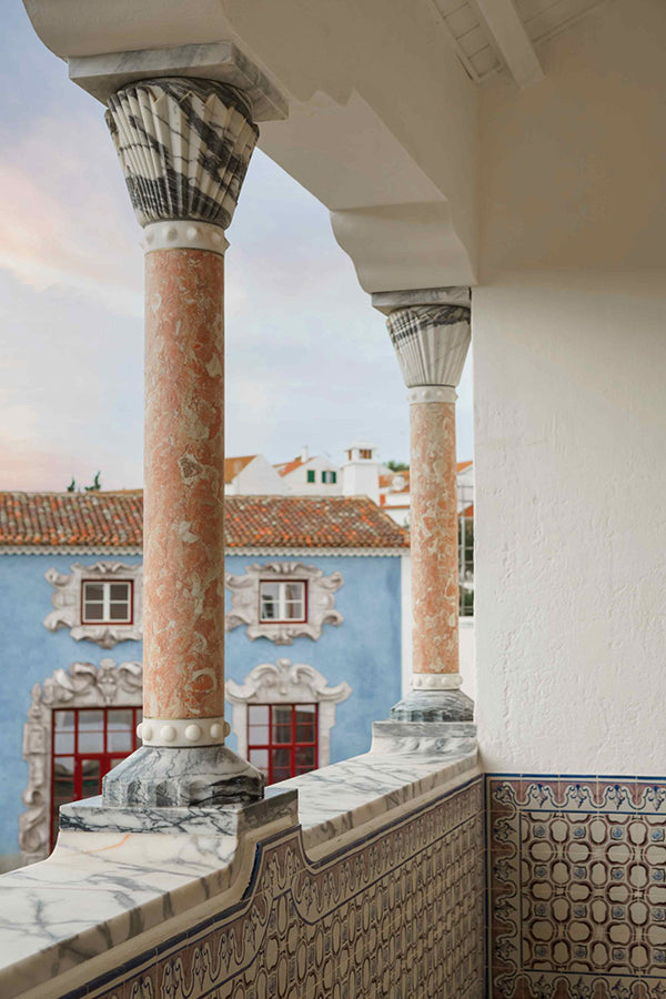 A balcony with marble columns and an azulejo half wall.