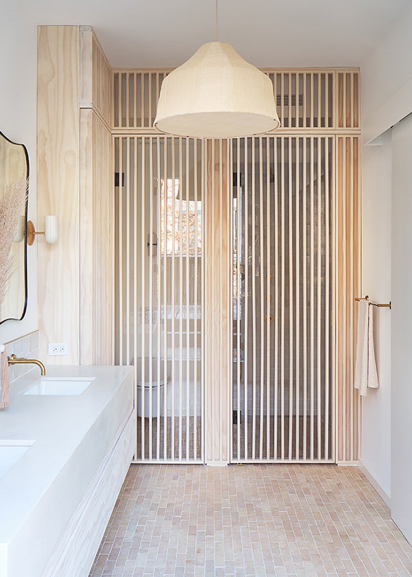 Modern looking wabi sabi style bathroom vanity area with natural zellige floor tile and wooden accents.