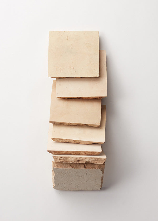 Several unglazed natural zellige tiles artistically laid in a row against a white background.