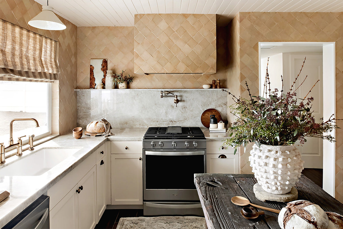 Tan zellige tile on kitchen walls with white lower cabinets and counters.