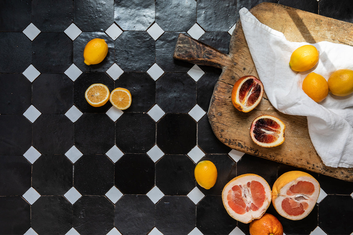 Overhead shot of black and white octogan tile with cutting board and lemons.
