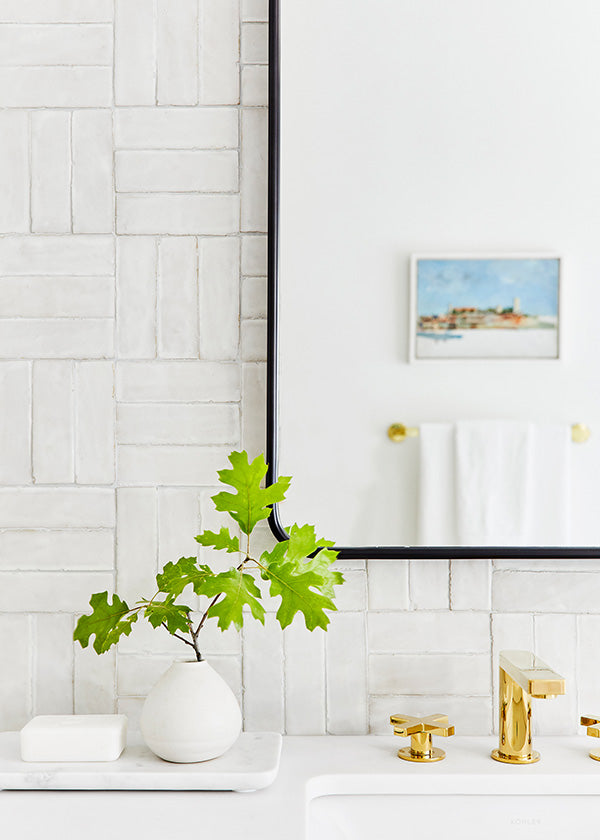 White bathroom sink area with white basketweave tile backsplash.