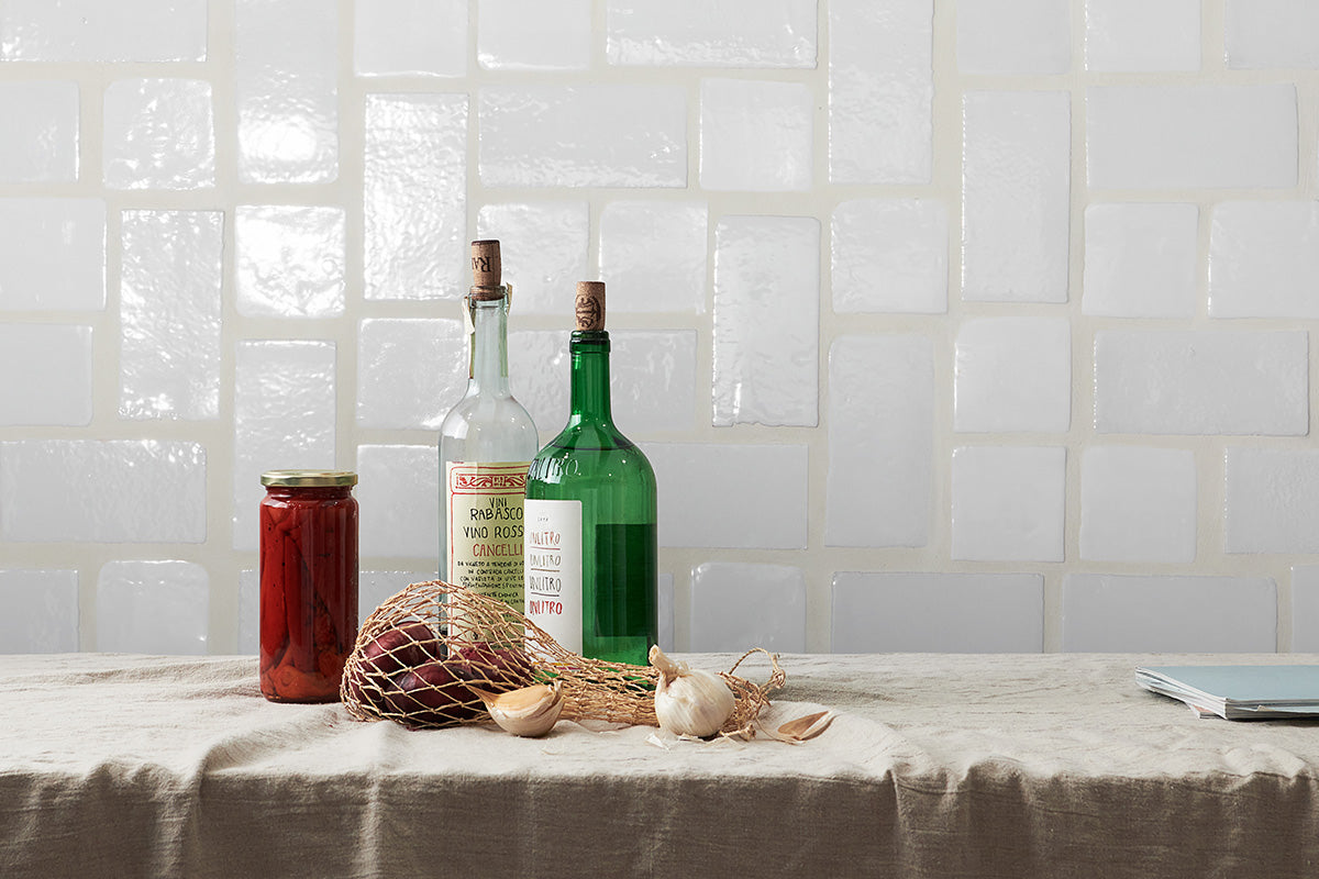 White glazed terracotta tile backsplash laid in an intricate pattern with varied tile sizes.