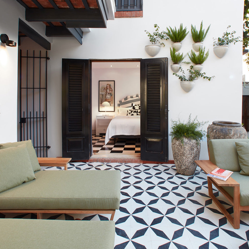 Beautiful patio off of bedroom with a patterned black and white cement tile floor and green lounge chairs.