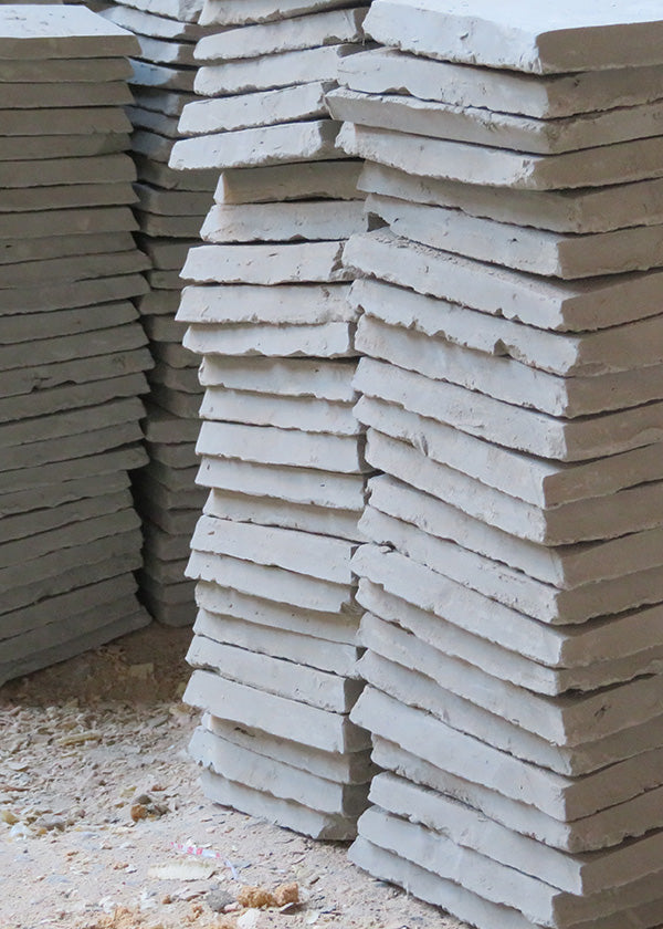 Closeup on tall vertical stacks of raw clay zellige tile that has not yet been fired or glazed.