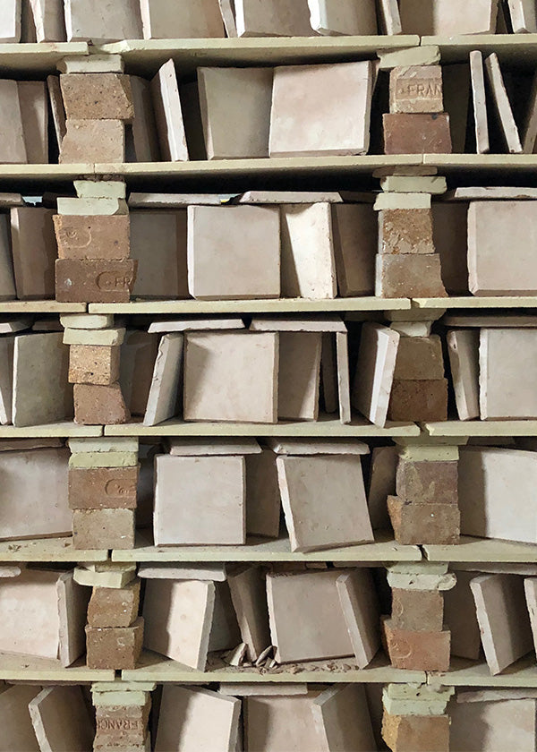 Rows and stacks of square zellige tile on a shelf waiting to be glazed.