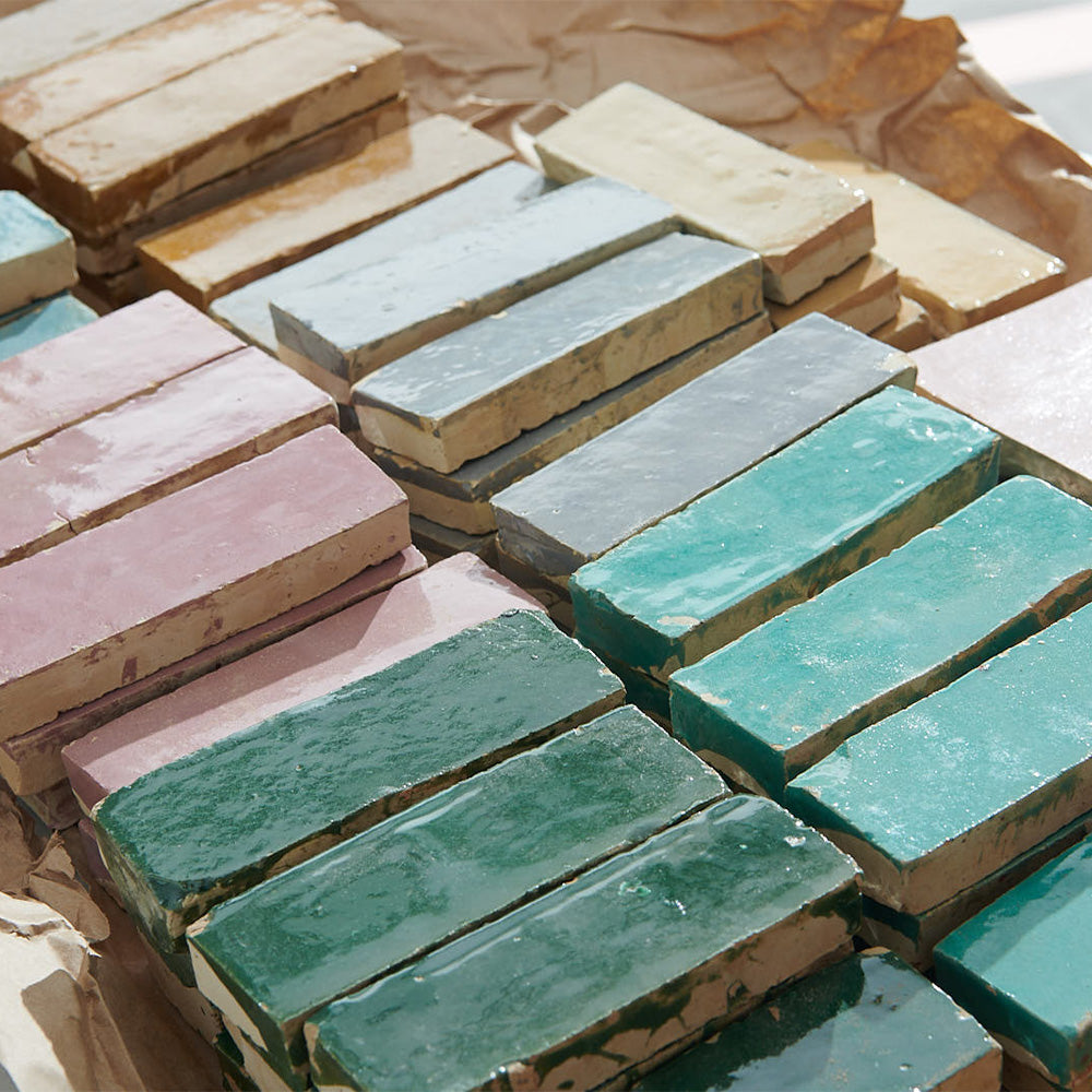 Stacks of rectangular zellige tile in varying shades of green, yellow, pink, grey, and blue.