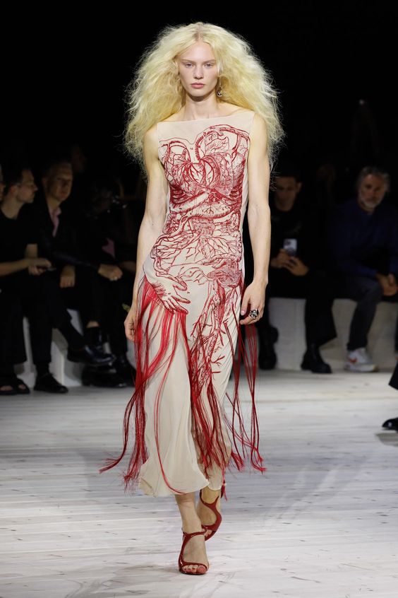 woman walking runway wearing Alexander Mcqueen nude and red tassel dress