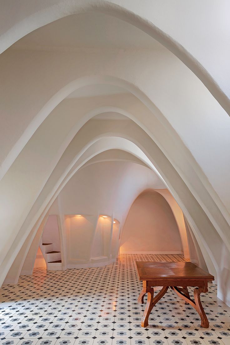 An interior with rows of white arched doorways and a white, black and grey tile floor.