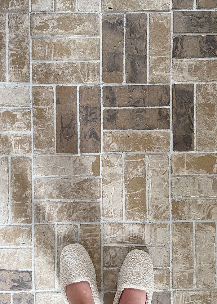 Overhead shot with tan basketweave tile floor with feet showing.