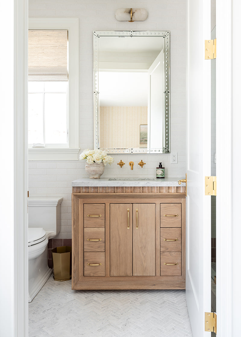 Attractive light-colored bathroom with white glazed brick herringbone floor and oak wood cabinet.