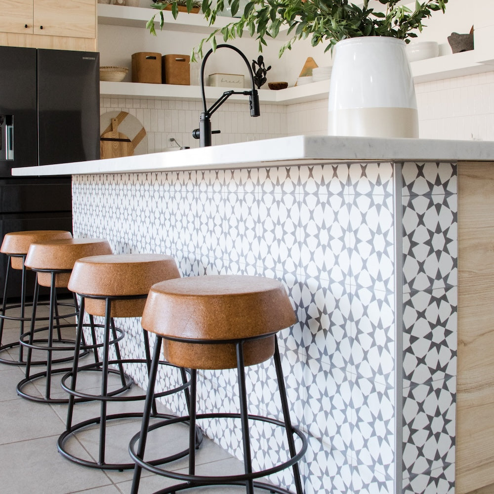 airy moroccan inspired kitchen with patterned white and grey tile along island barstool area