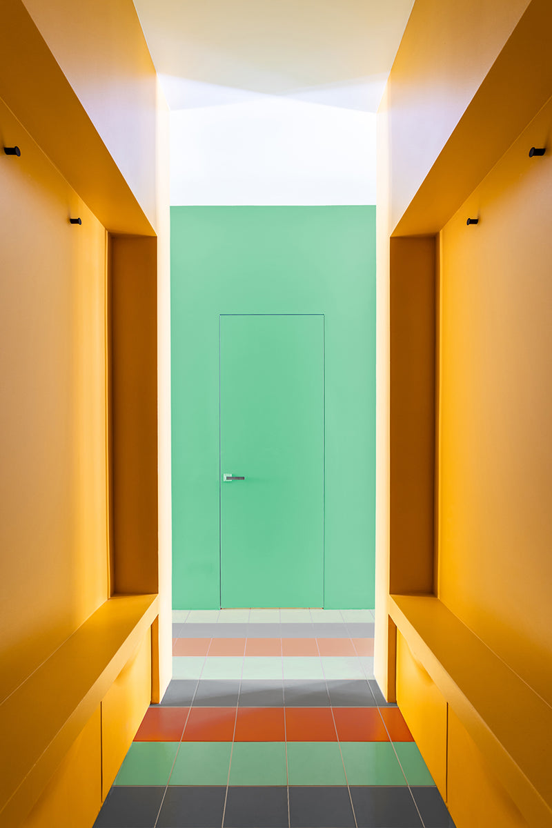 A hallway with white plaster walls and a dark tile floor.