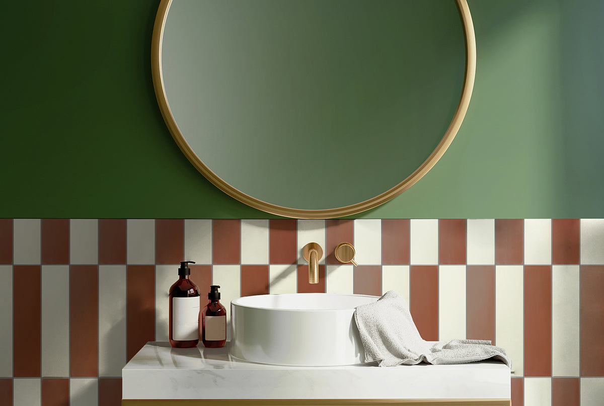 Earth toned bathroom vanity area with green wall, checkered white and rust cement tile, and white sink.