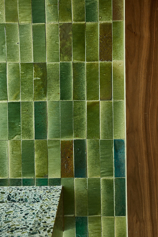 Irregular jade green tiles on a wall.