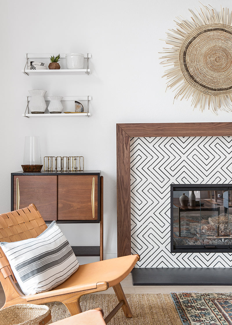 Modern neutral colored living room with beige leather chair and a black and white geometric cement tile fireplace surround.