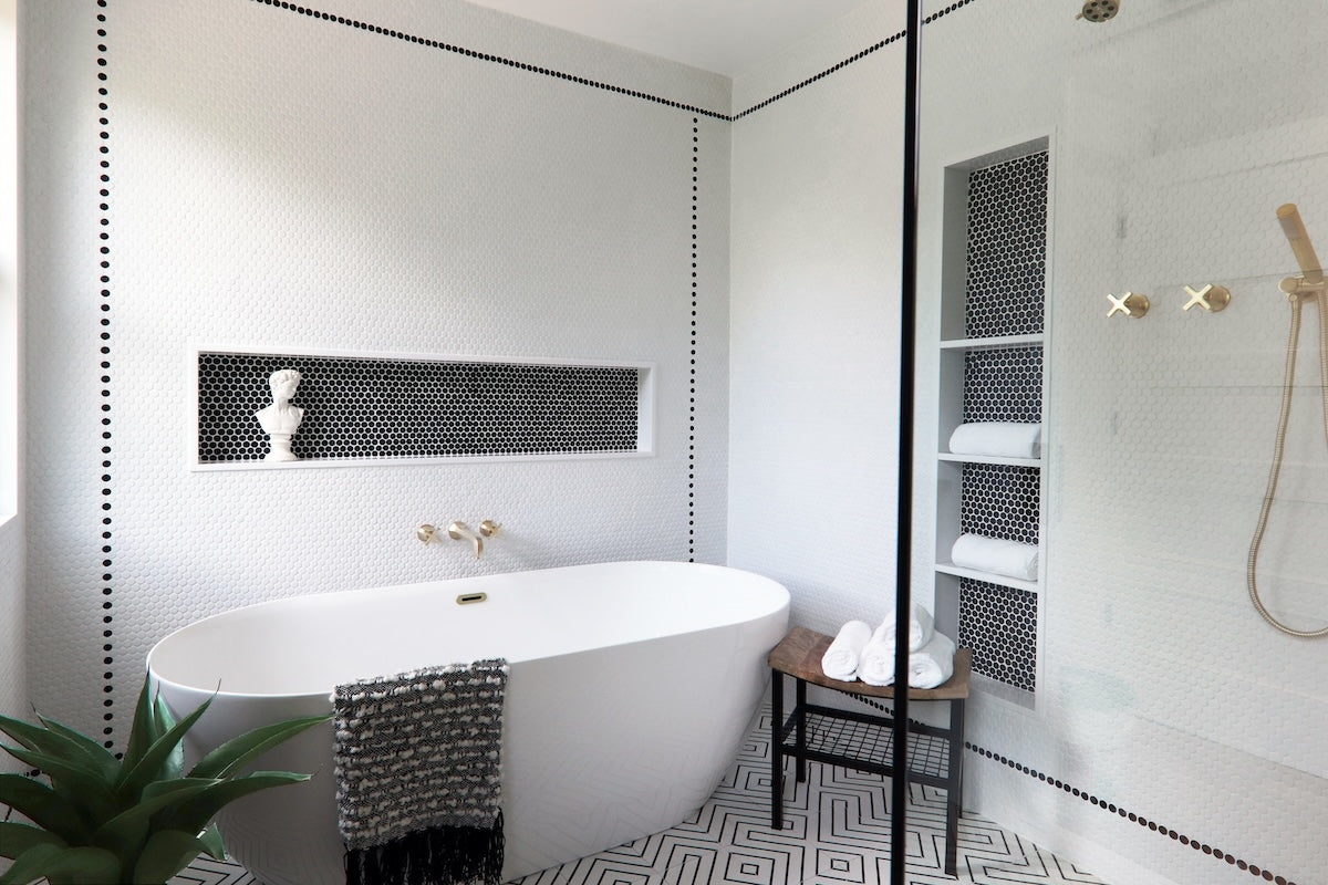 classic black and white tub area with white penny tile wall and black penny tile niches
