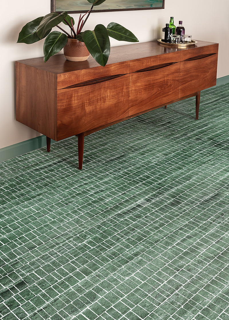 Angled shot of green rough cut mosaic tile floor with a mid century modern credenza.