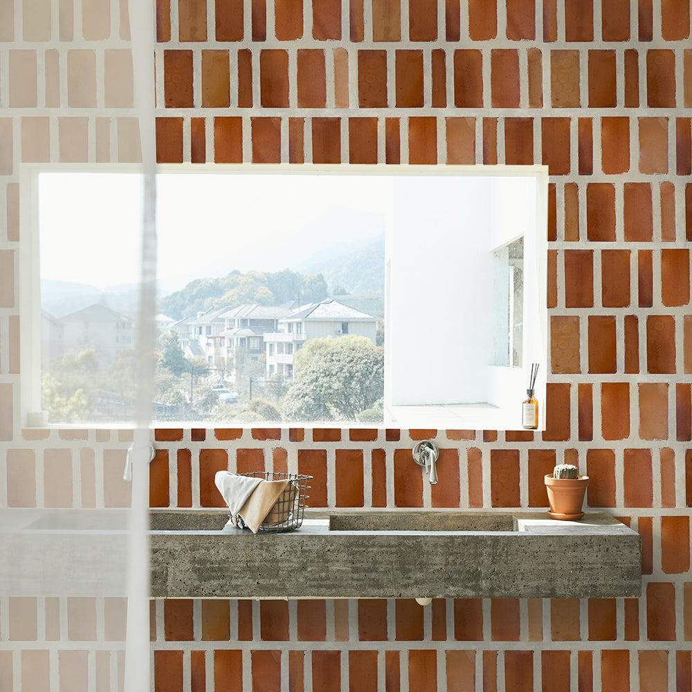 A sunlight bathroom sink vanity with a terracotta tiled wall and beautiful view overlooking villas.