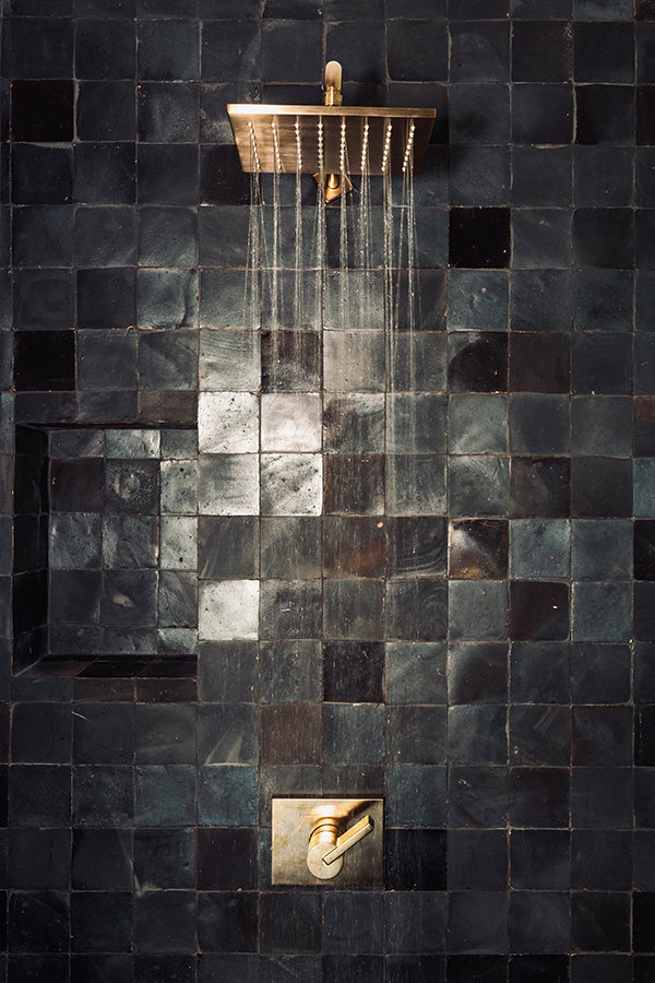 Square black and charcoal semi-glossy tiles on a shower wall.