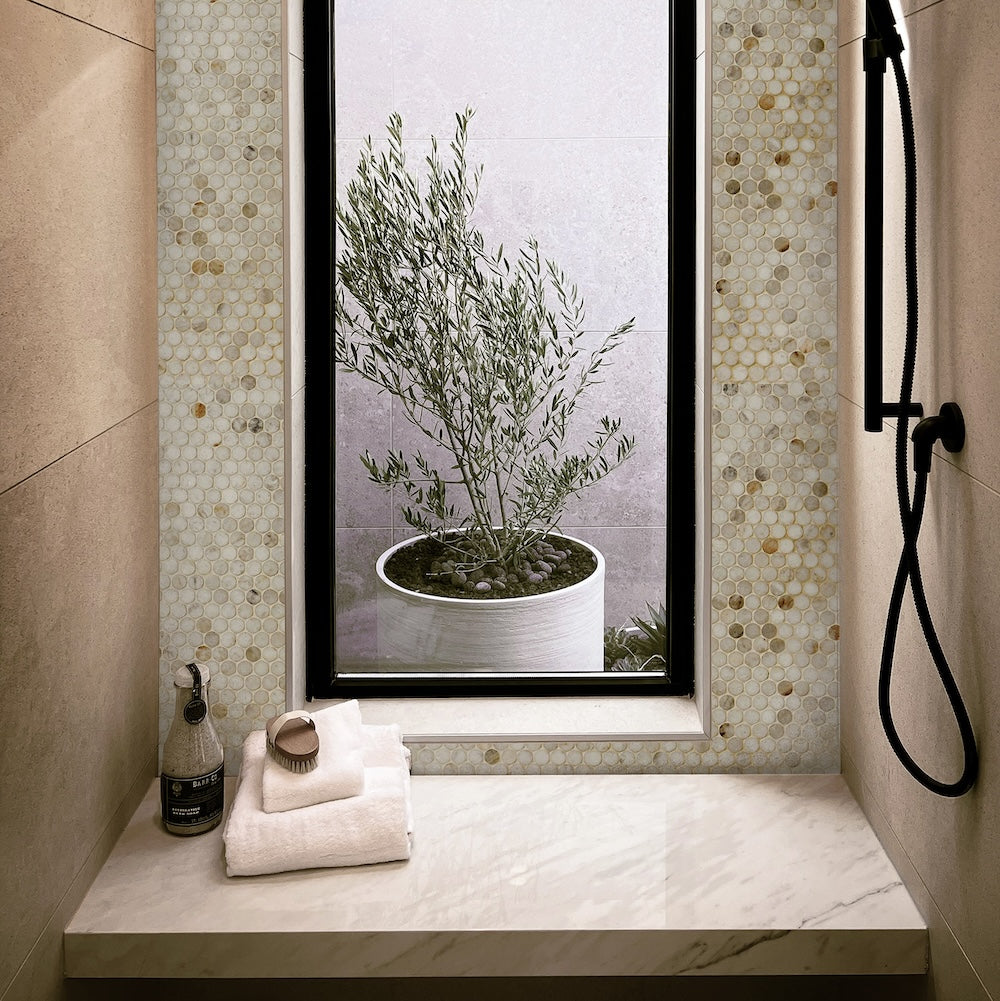 tan colored bathroom nook with marble penny tile and large limestone tile on the walls