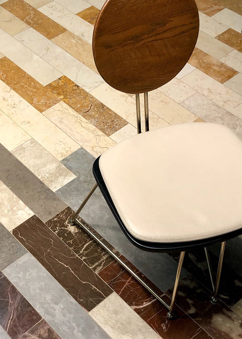 Top-down shot of various types of rectangular stone tile laid on a floor with a modern chair on top.