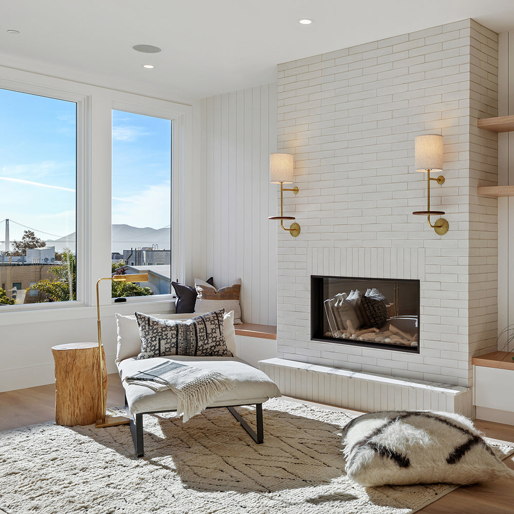 Sunlit living room with soft white textural decor and a white glazed terracotta tiled fireplace surround.