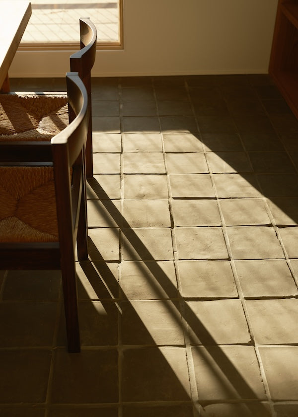 sunlight hitting an unglazed grey terracotta tile floor in kitchen