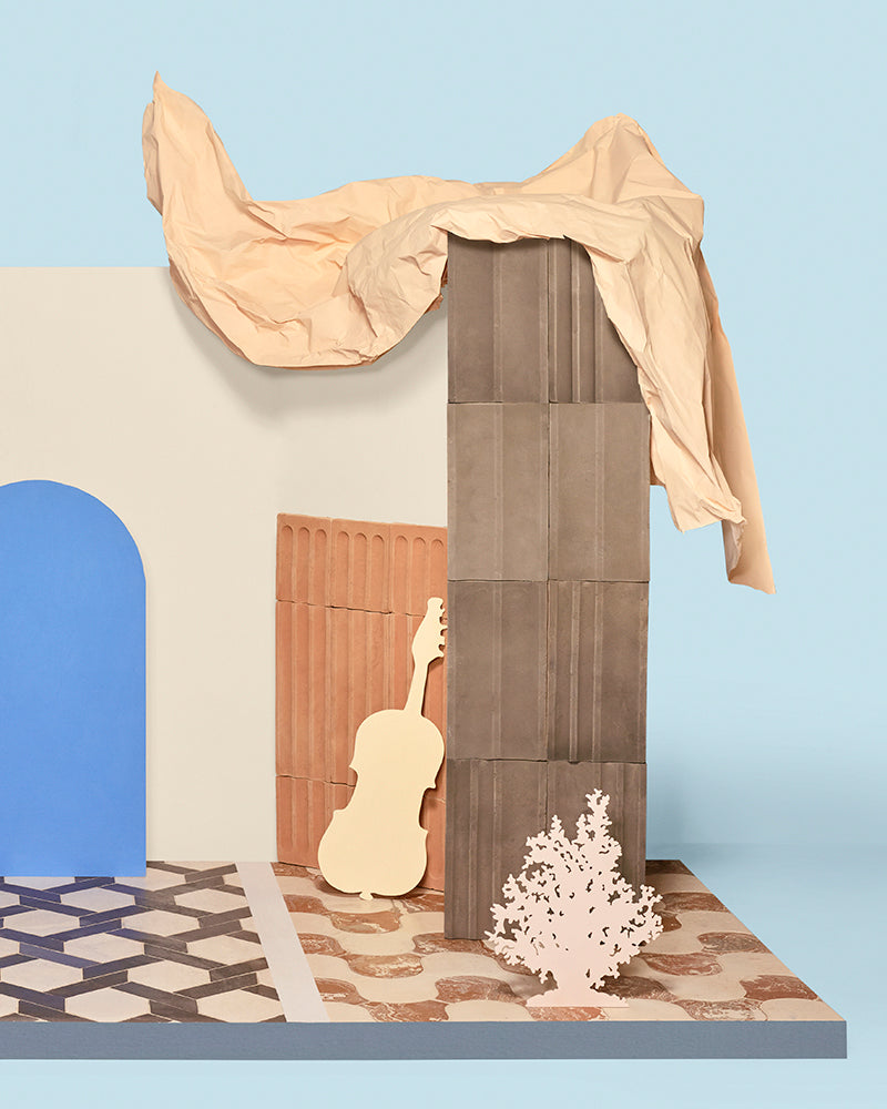 Scene against blue background with two types of patterned stone tile floors and a white wall with props.