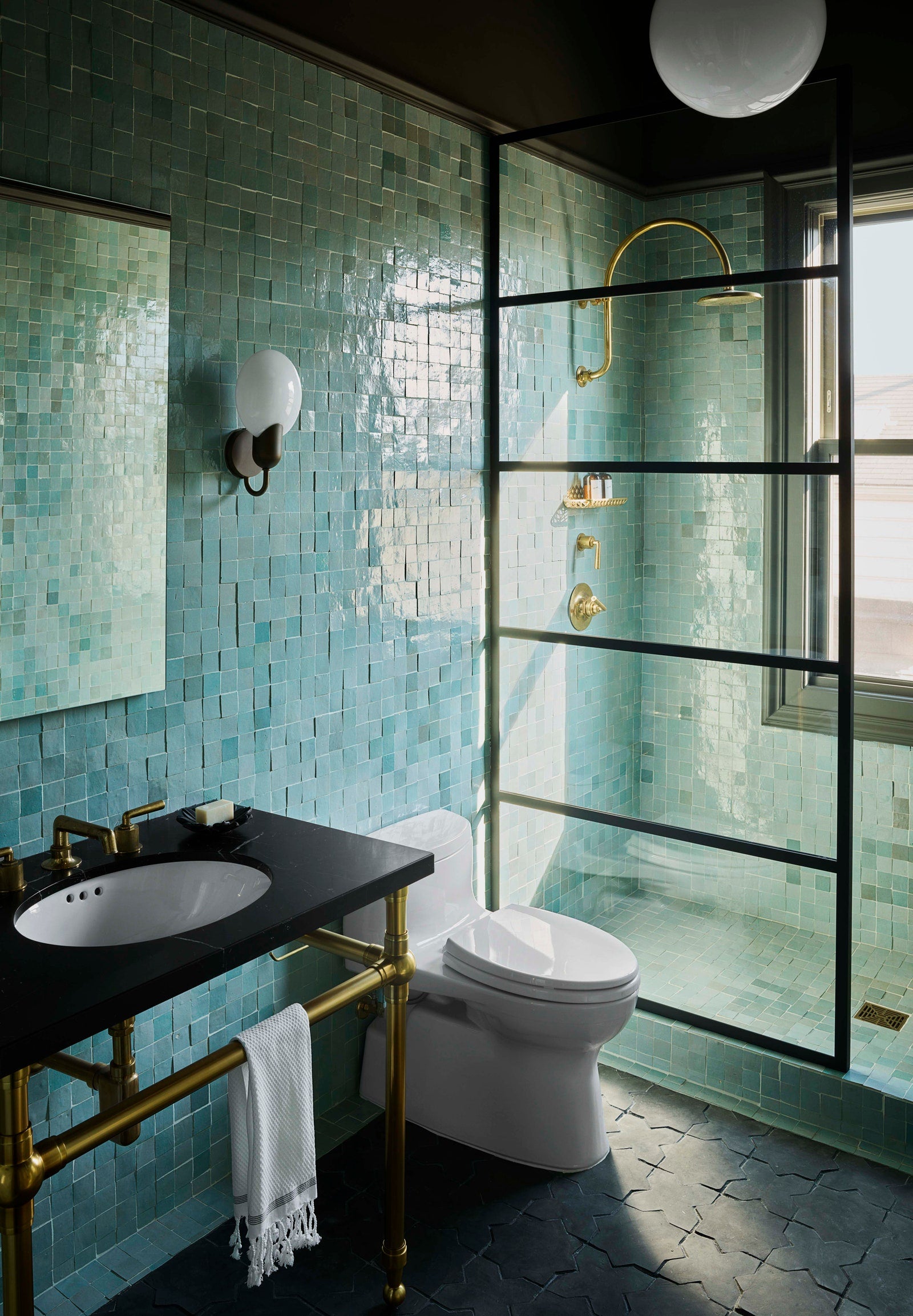 moody bathroom with teal tile walls and dark tile flooring