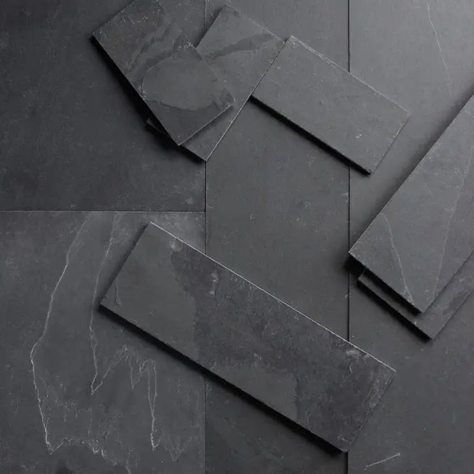 A selection of dark grey slate natural stone tiles laid over each other.