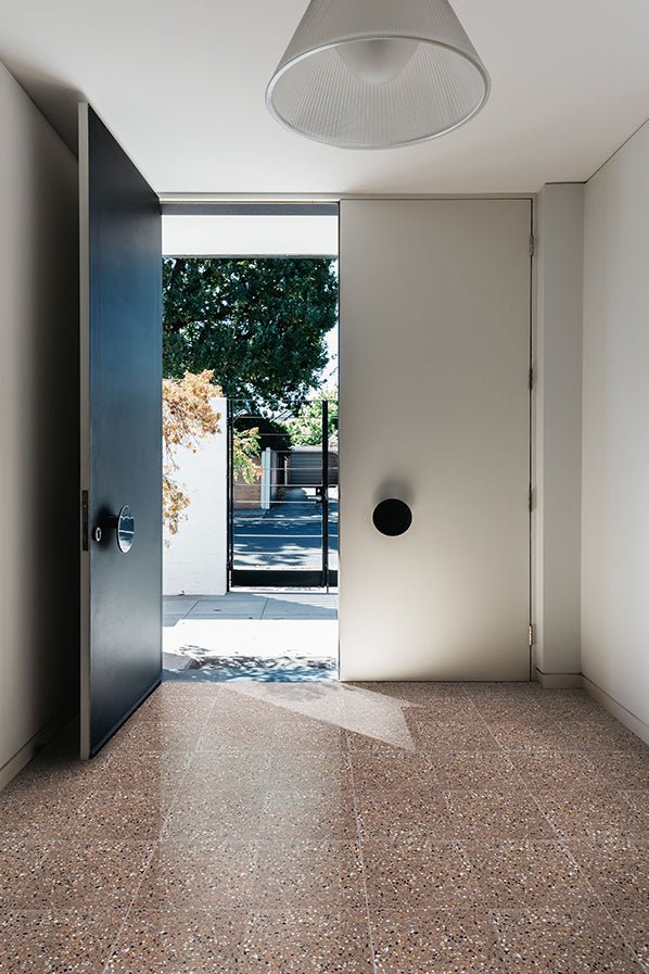 Sunlit modern entryway with light brown square terrazzo tile flooring and an open door.