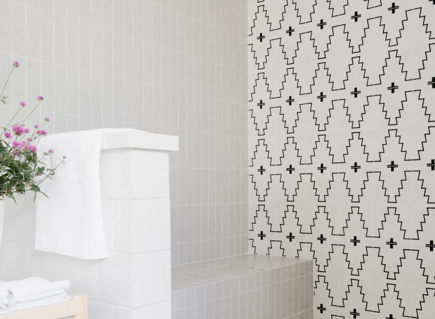 A grey tiled wall with a debossed modern pattern and a brown leather couch.